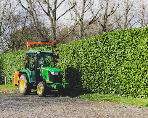 Hedge trimming at a campsite near Diss, Norfolk using John Deere tractor with a Ryetec scissor attachment